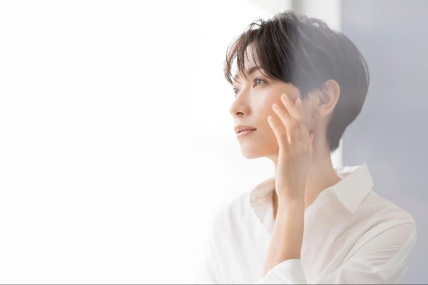 たるみを気にして頬に触れる40代女性