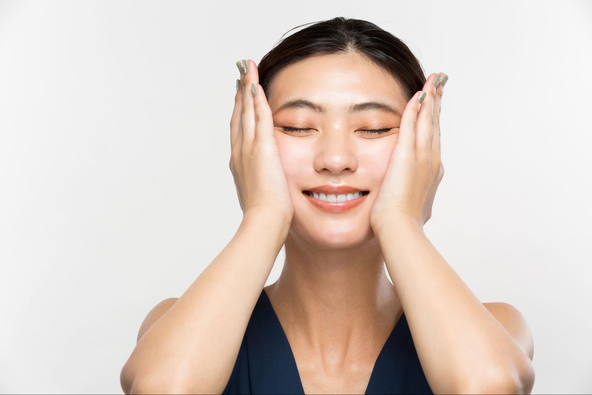 頬のたるみを両手で引き上げている女性
