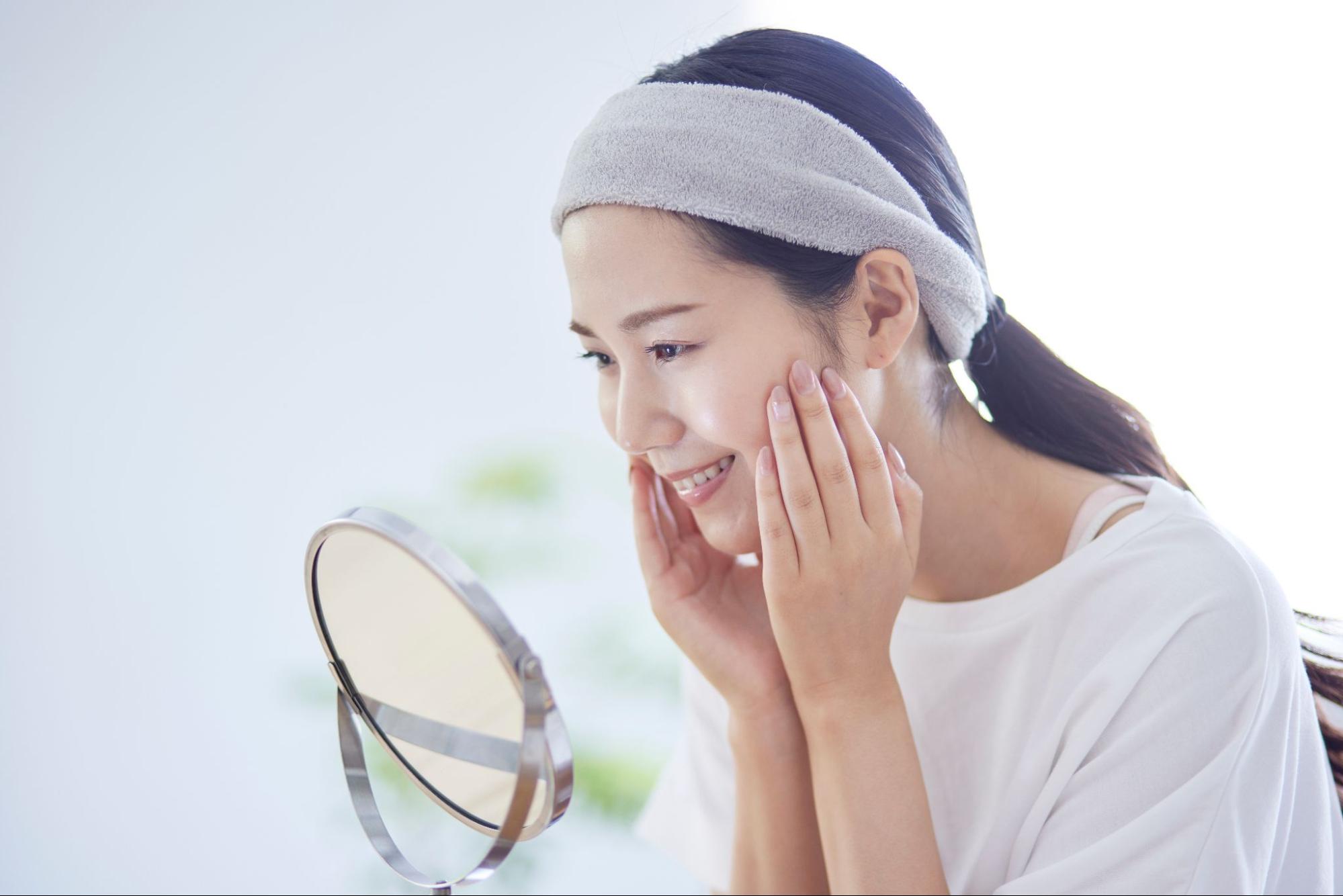 鏡を見ながらスキンケアをする女性