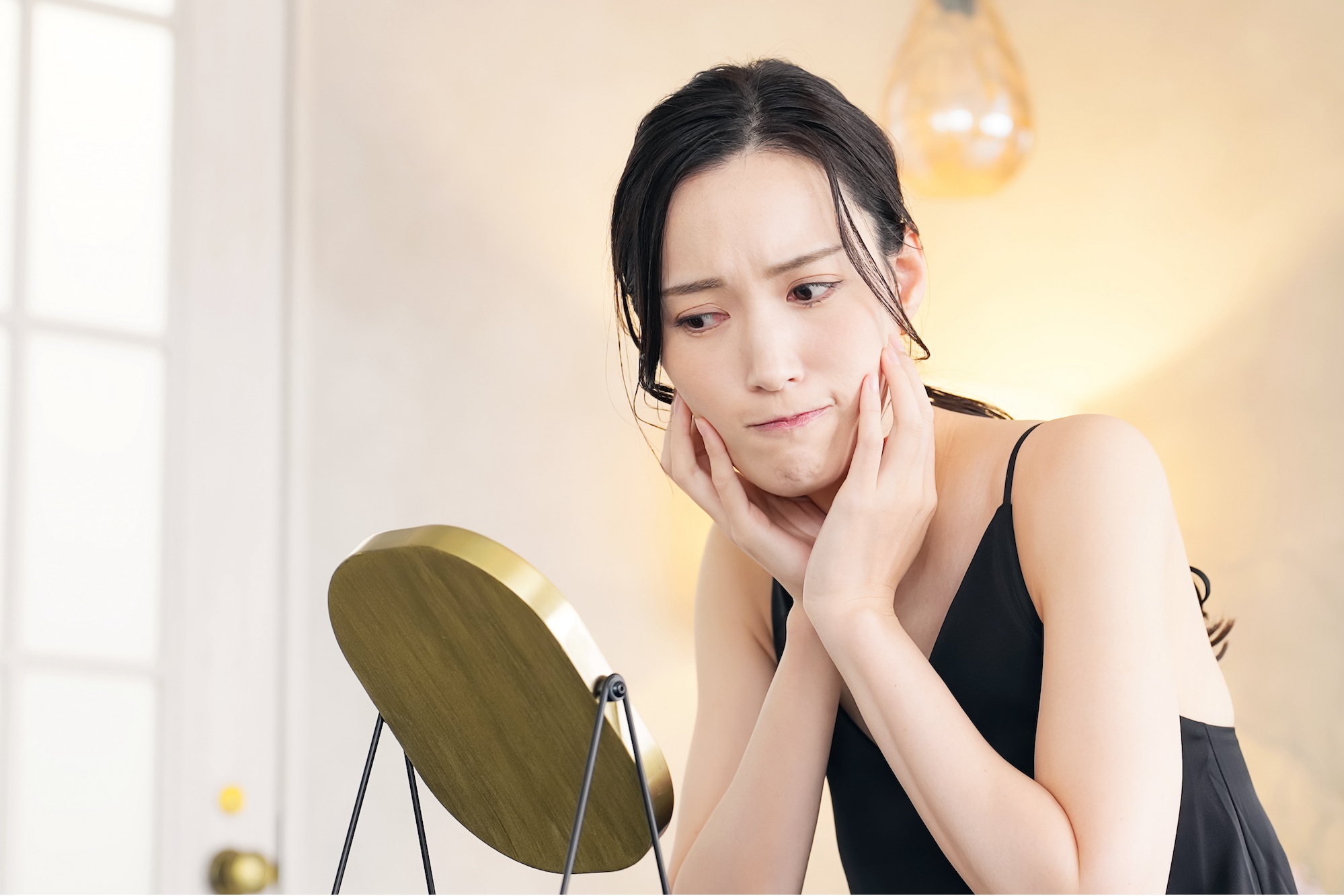 鏡を見て悩む女性