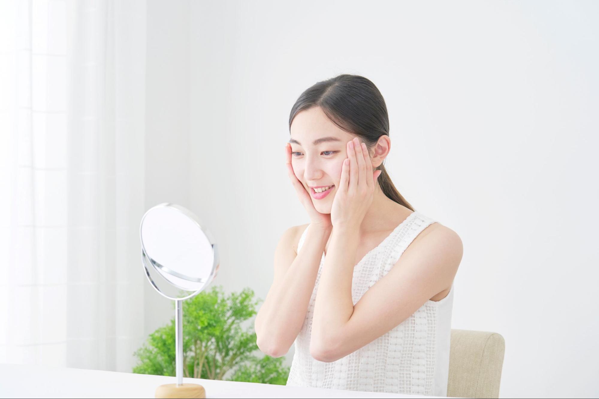 鏡を見ながら頬を触る女性