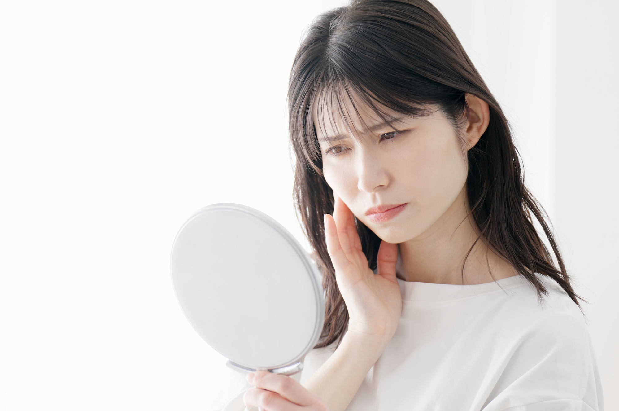 鏡を見て悩む女性