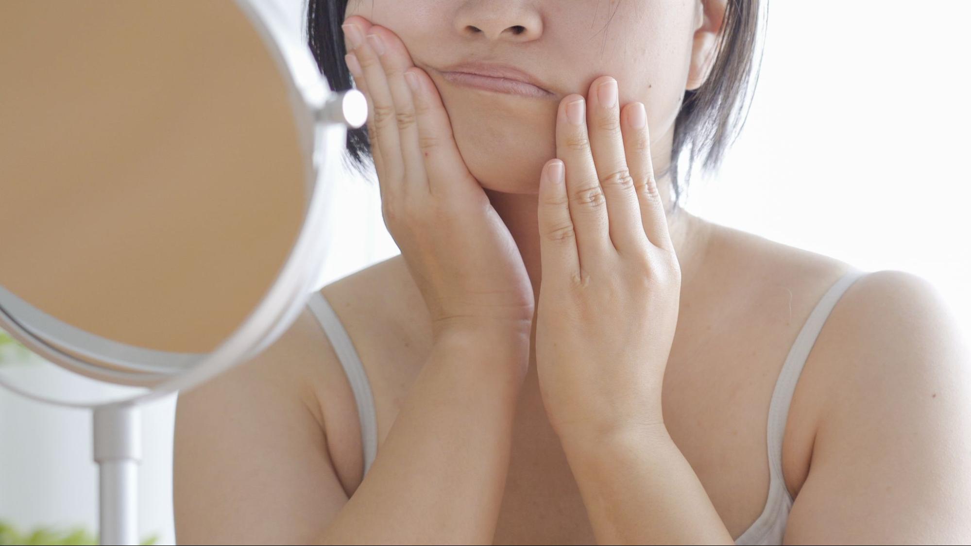 鏡を見てセルフケアをする女性
