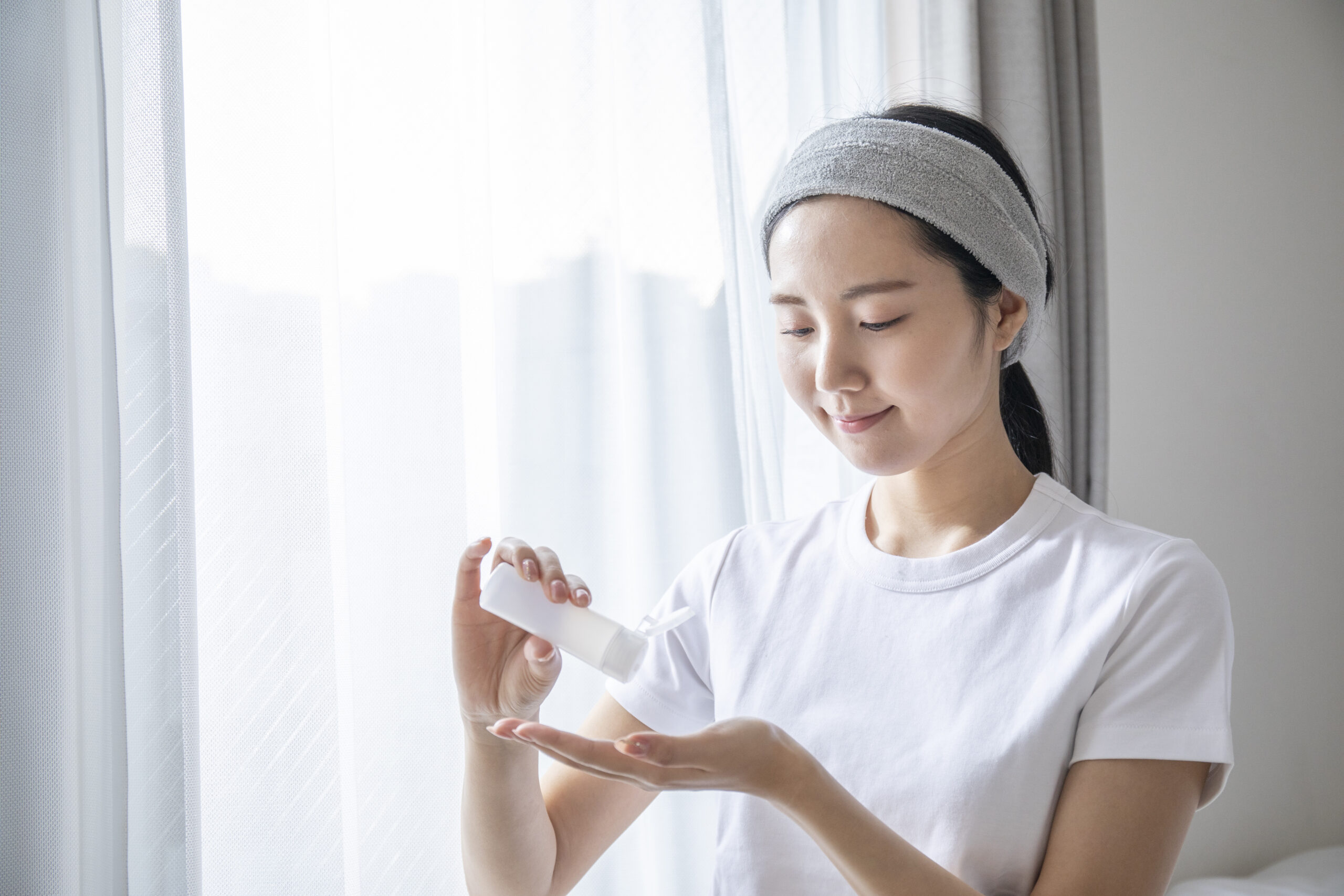 部屋でスキンケアをしている日本の若い女性