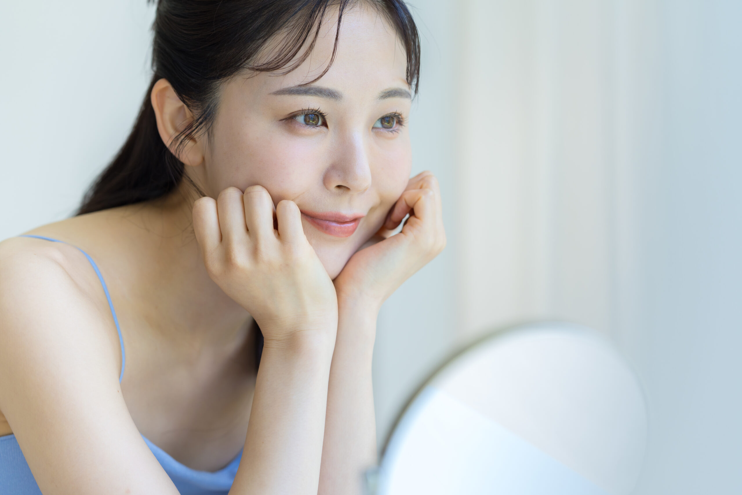 鏡を見ながらりょうととに手を当てている女性